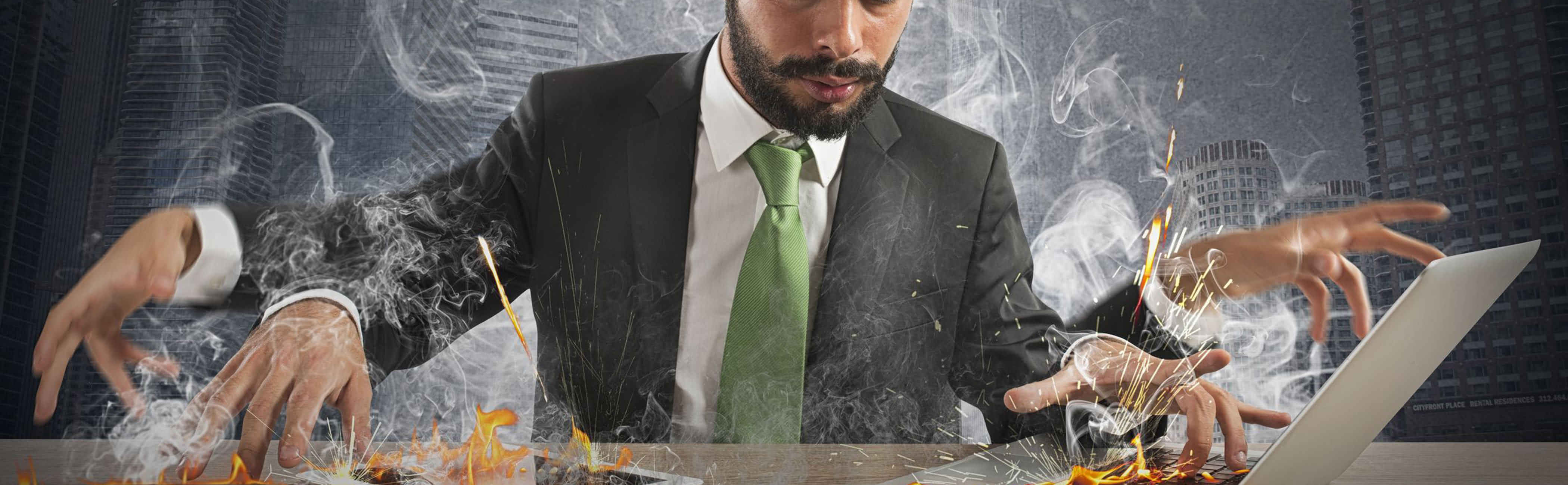 Businessman working so fast, flames lick out of his computer and phone.